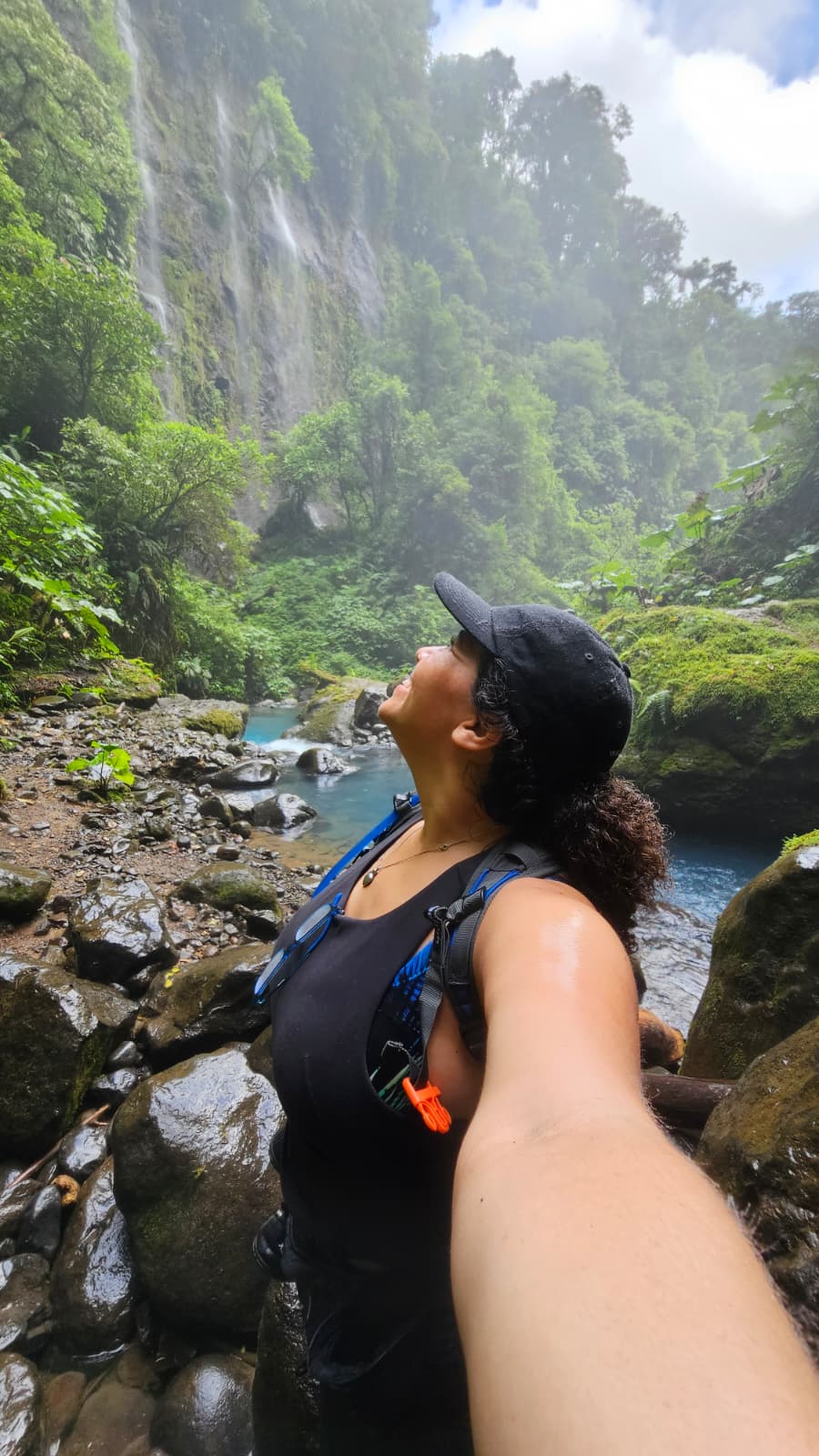Lucie McGuire beside a waterfall while traveling